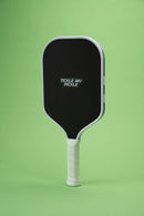 TMP Stealth Pickleball Paddle on a green background, full body view showing the Tickle My Pickle wordmark and white edge frame